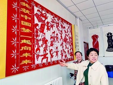 大港剪纸传承人单瑞金(左)和孙艳秋介绍中国梦主题的剪纸作品.
