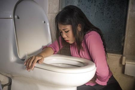 恶心呕吐年轻的醉酒或怀孕的亚洲妇女呕吐和呕吐在厕所wc感觉不适和