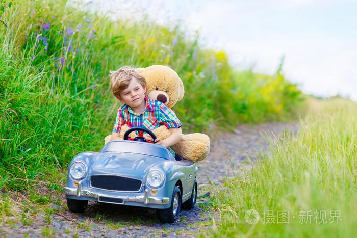开车的大玩具和一只熊,在户外的小小孩男孩