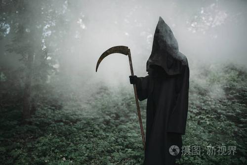 死在黑色的帽衫和在黑暗的薄雾森林的镰刀.