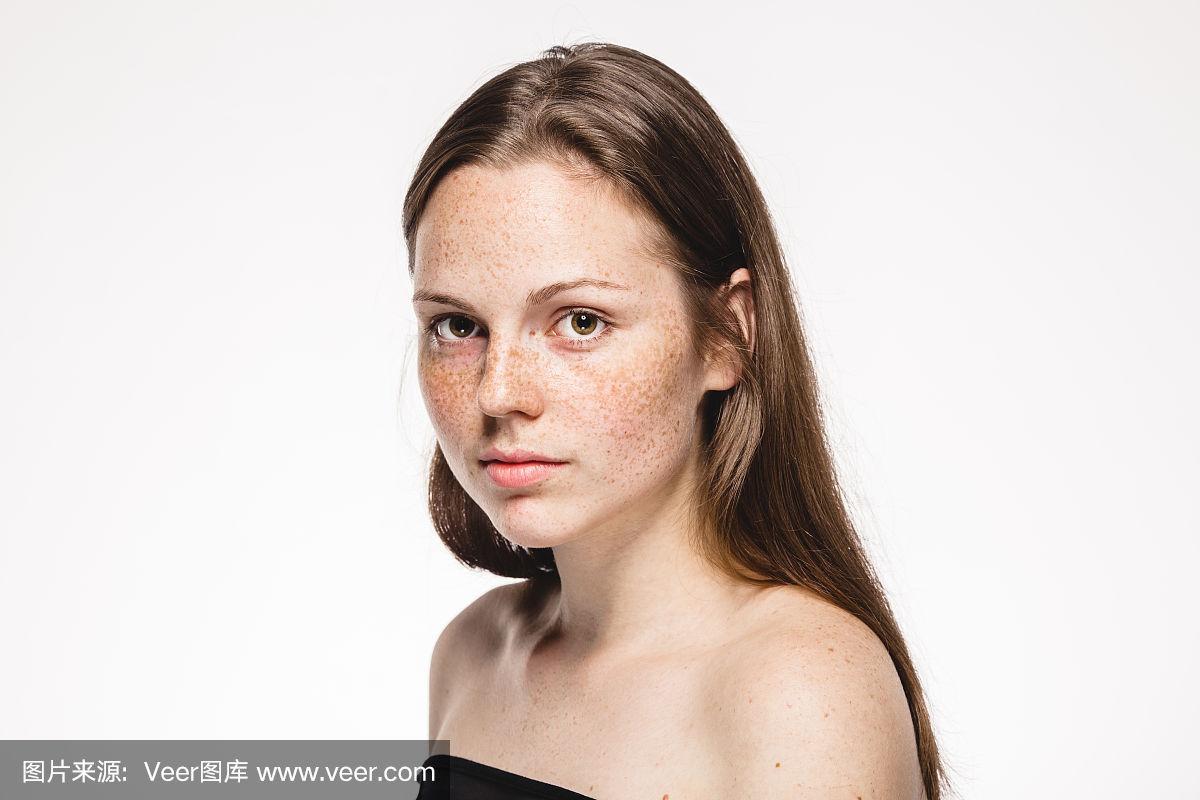 年轻美丽的女人脸上的雀斑肖像与健康的皮肤