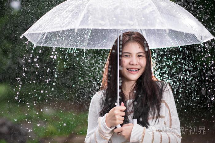 透明伞雨中快乐的亚洲女孩