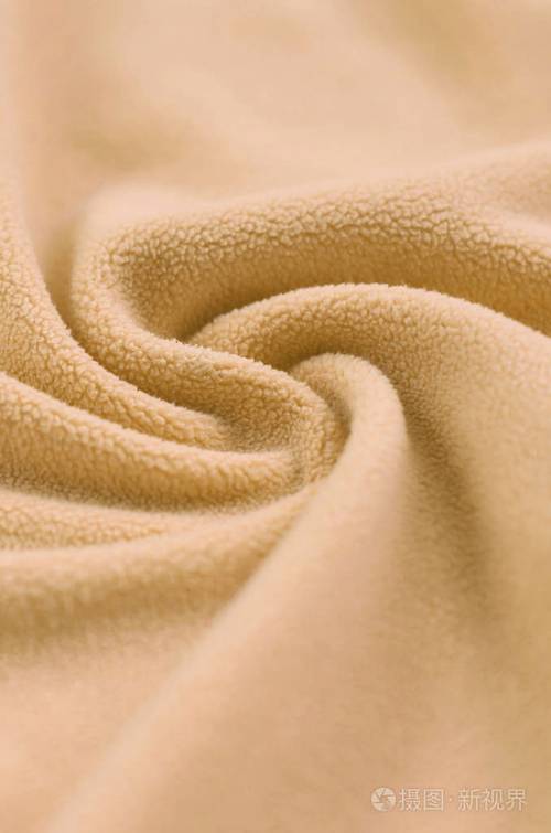 毛茸茸的橙色羊毛布的毯子浅橙色软毛绒绒材料的背景与大量浮雕褶皱
