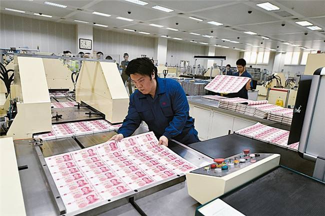 北京印钞有限公司工作人员将印制完成的大张新版百元钞票摆放在机器上