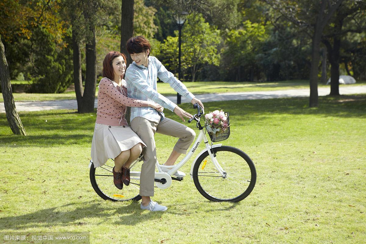 情侣在公园里骑自行车的照片