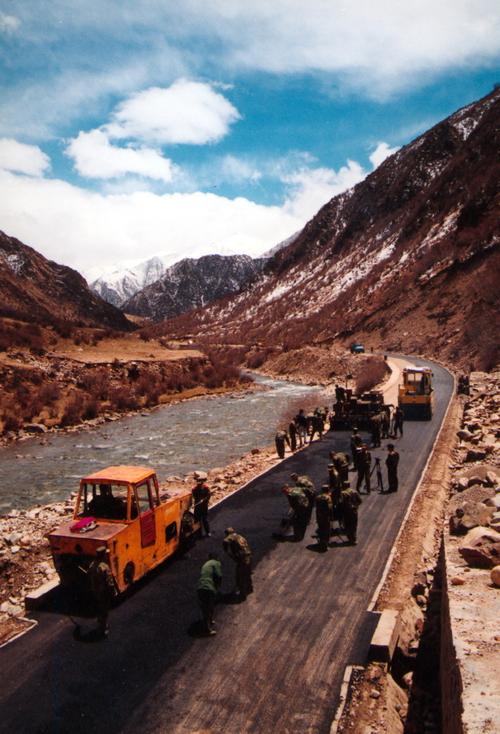 原武警交通二支队官兵在川藏线上摊铺沥青路面