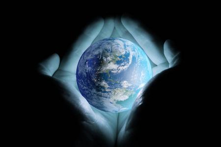 男人的手捧着行星地球在黑色的背景下以蓝色的光芒旋转着北美洲和南美