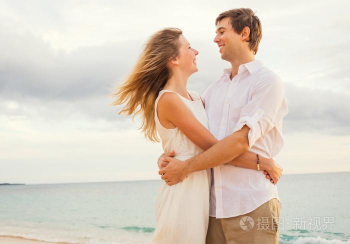幸福浪漫的情侣拥抱对方的存在的日落海滩上