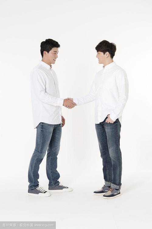 两个穿着白衬衫的男人手牵手站立的照片
