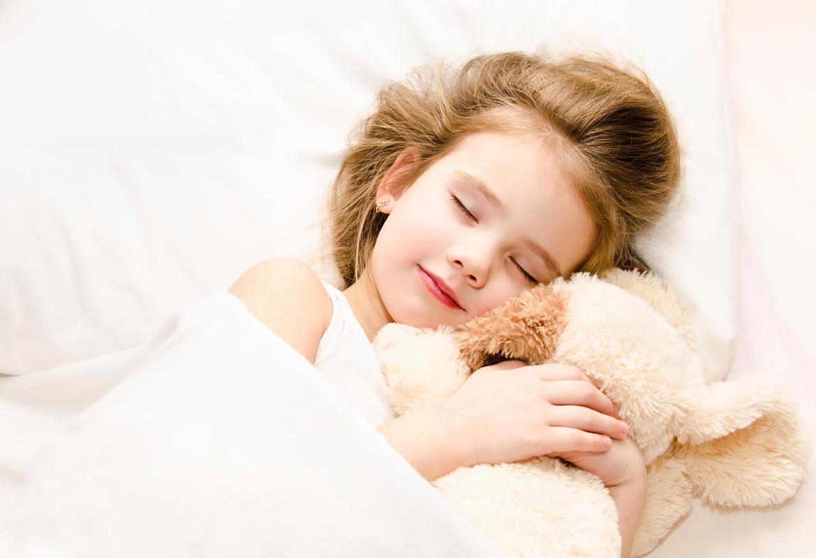 可爱的小女孩睡在床上有她的玩具微笑的小女孩