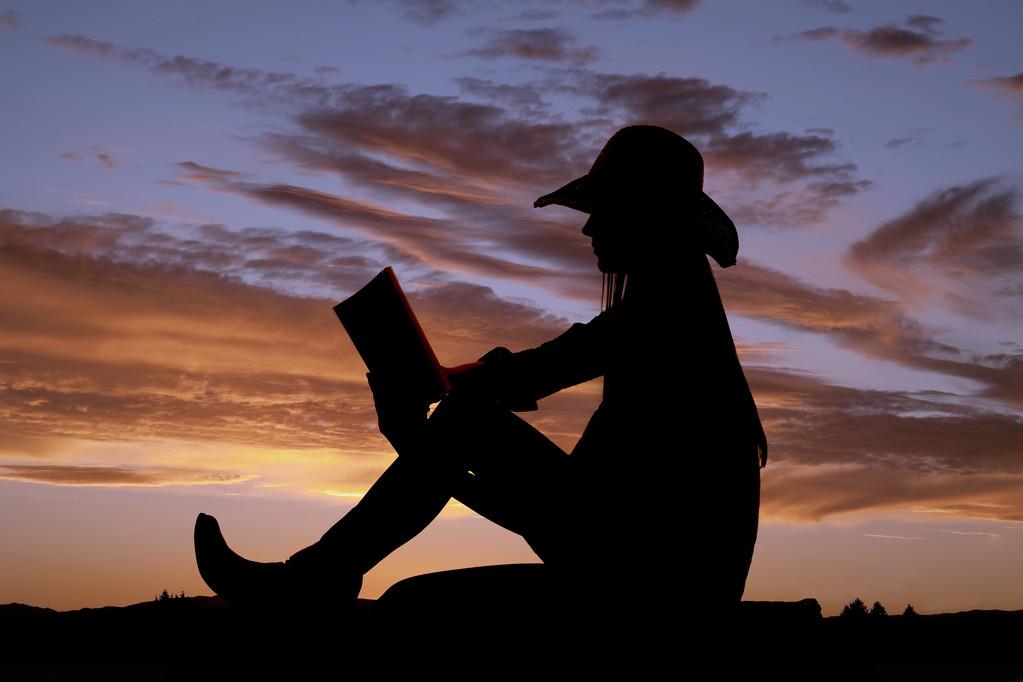 阅读本书的剪影坐,女牛仔坐和读她的书与大自然.