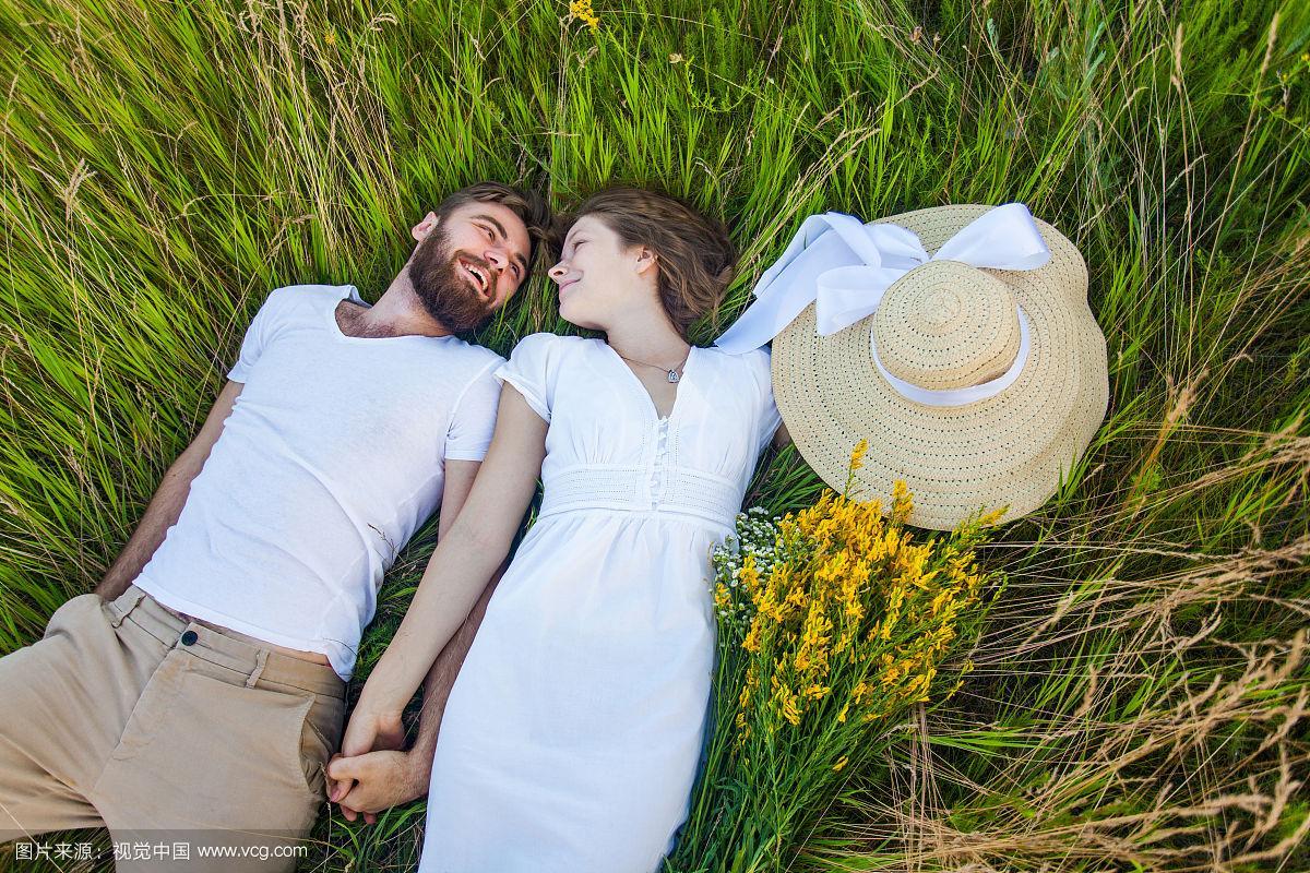 快乐的年轻夫妇在爱躺在草地上.