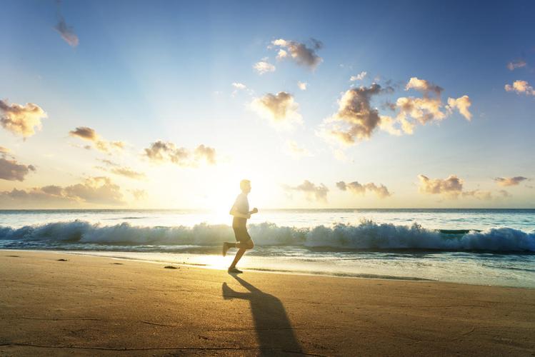 日落时在热带海滩上奔跑的人坚持运动健身户外跑步