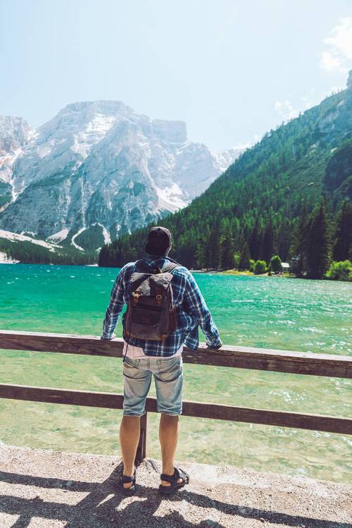 背着背包的男人站在山上看湖