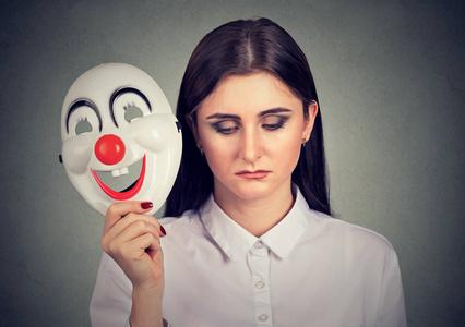悲伤的女人脱下表达快乐的小丑面具面部表情一套在接听电话时从快乐