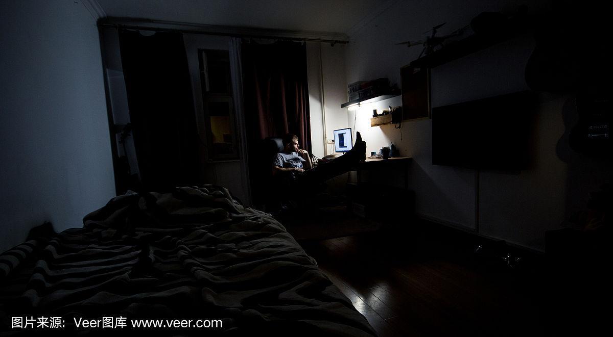 人们工作,晚上在家里的房间里,在黑暗中,在电脑前休息