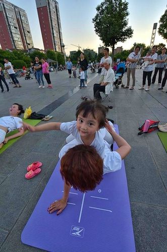 年6月20日,西乡樱花广场上,一位可爱的小姑娘骑在练瑜伽的奶奶身上