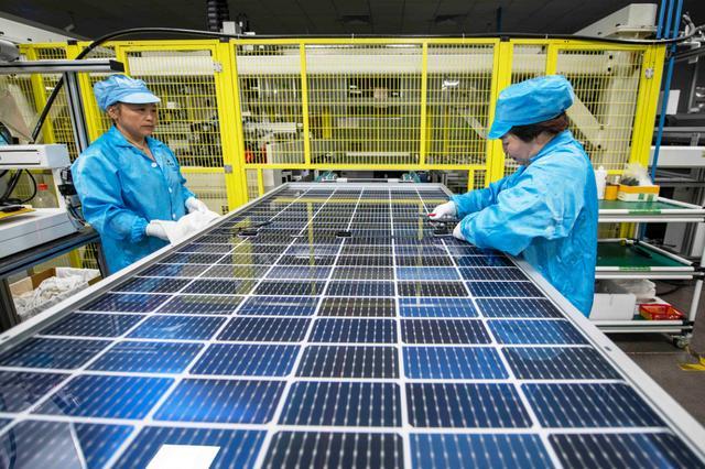 车间里,自动化生产线高速运作,工人们在有序地忙碌生产太阳能光伏组件