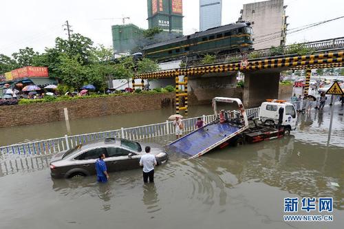 6月13日,在广西柳州市广雅铁路立交桥底,救援人员转移被水淹的汽车.