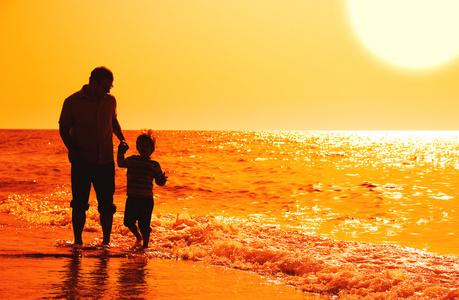 孩子与他的父亲在海上日落照片