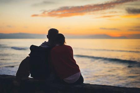 情侣拥抱背景海滩海洋日出剪影两个浪漫的人拥抱和仰望后景傍晚海景潮