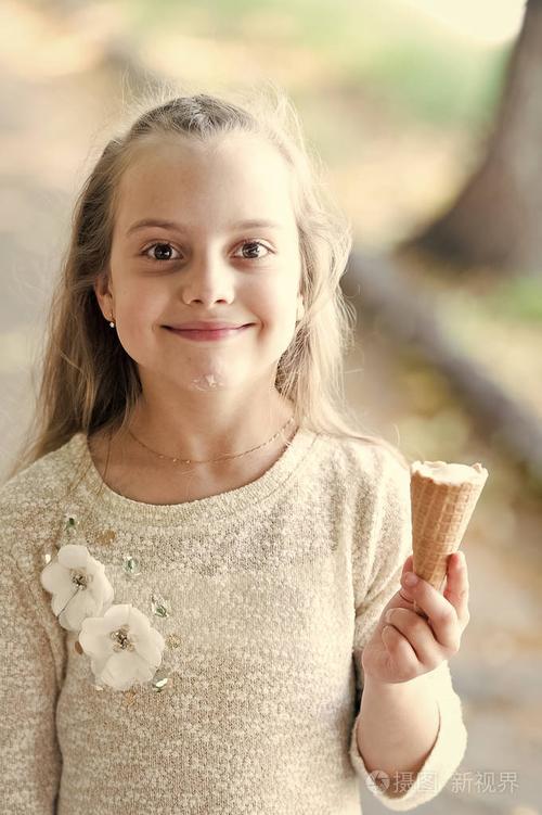 小女孩喜欢吃冰淇淋.快乐的孩子与冰淇淋锥在阳光明媚的户外.