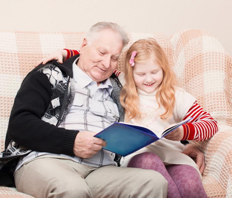 爷爷和孙女坐在沙发上和阅读博