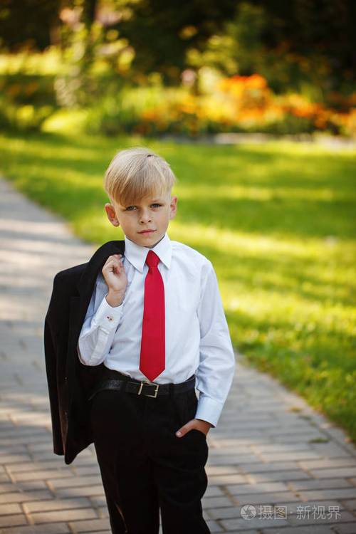 画像严肃的小男孩穿西装和红色领带在自然背景