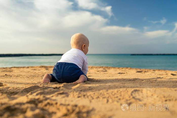 小男孩在海滩上玩蹒跚学步的孩子坐在沙滩上散步美丽的励志海滩和海洋