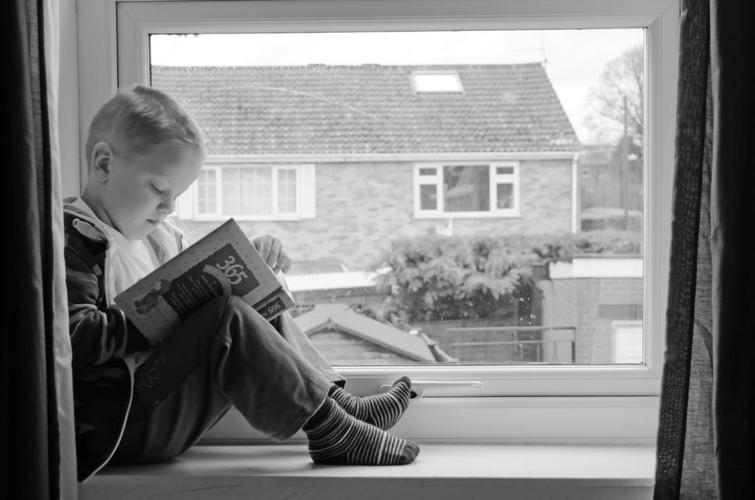灰白人放松窗边看书的男孩背景图片
