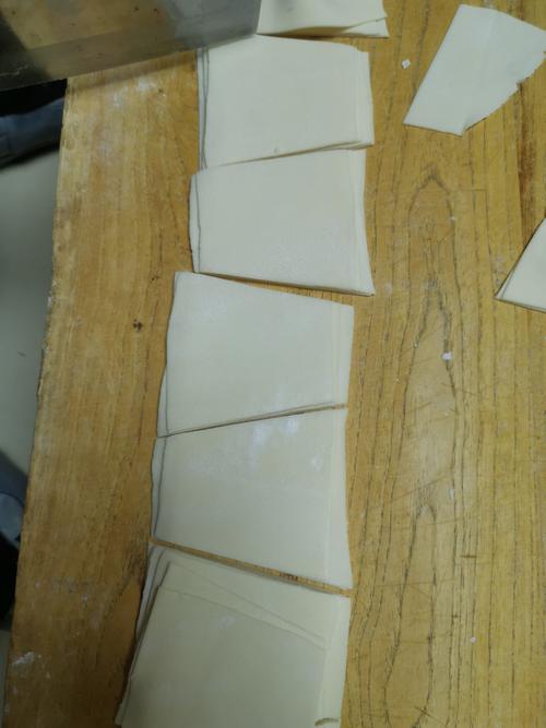 再把这张饼叠好,切出一个个梯形的形状,元宝水饺饺子皮就做好了.
