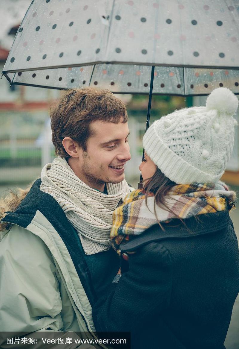一对年轻情侣在雨天的雨伞下拥抱在一起