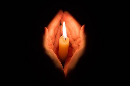 双手捧蜡烛祈祷手里捧着燃烧蜡烛在黑暗像一颗心照片