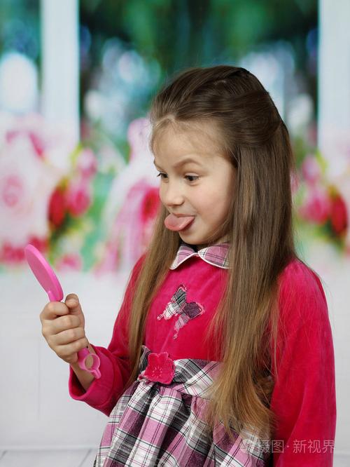 可爱的小女孩在镜子中显示她的舌头
